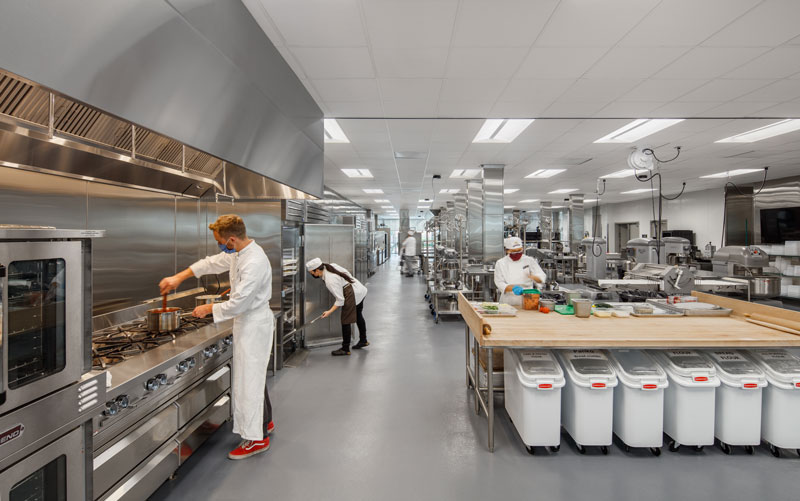 Los Angeles Trade Tech College. Commercial kitchen with thee chefs preparing food.