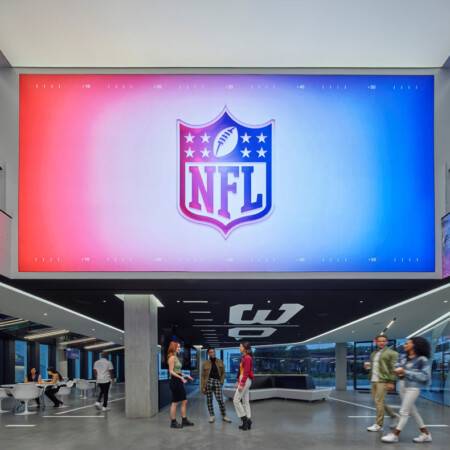 NFL Los Angeles Commissary. NFL logo displayed on large screen with people congregating underneath.