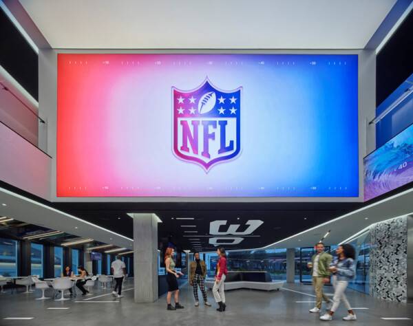 NFL Los Angeles Commissary. NFL logo displayed on large screen with people congregating underneath.